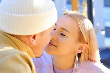 Kiss of a beautiful and young couple in love on a sunny day in a street cafe. Horizontal photoの写真素材