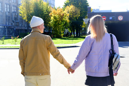A couple in love, a guy and a girl, walks around the city and holds hands. Horizontal photo