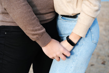 A young couple is holding hands. Hands shot close up. Horizontal photo