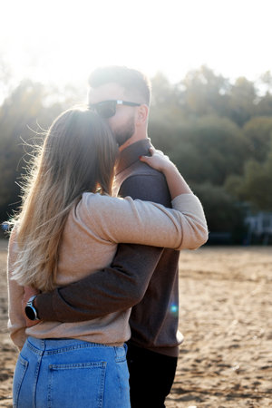 A young man hugs a girl by the waist. couple standing with their backs to the camera. Vertical photoの写真素材