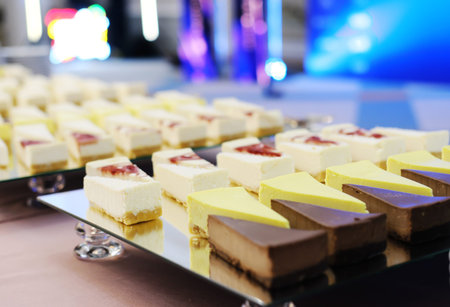 Pieces of cheesecakes on a mirrored tray on the buffet table. Horizontal photo