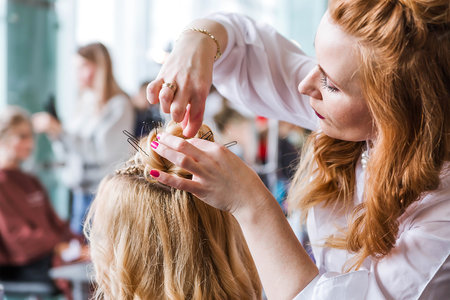 Competition stylists hairdressers at the exhibition of hairstyles and makeup. Hairdresser creates hairstyle for his model. Horizontal photoの写真素材