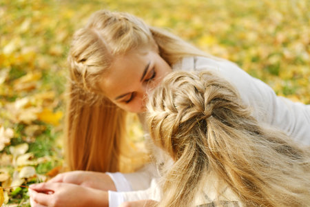 The family spends time together in the park. Girl and mother lie on a blanket and talk. Horizontal photoの写真素材