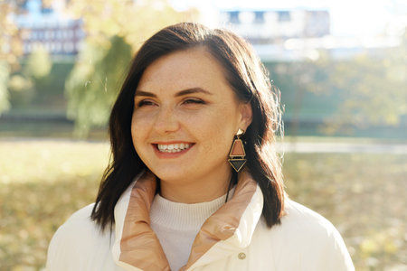 Beautiful brunette woman with freckles on her face smiles and looks into the distance. Young woman...