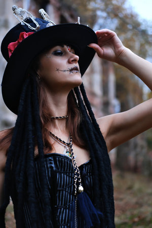Female look for Halloween. Make-up woman in a black corset and top hat decorated with skeleton...