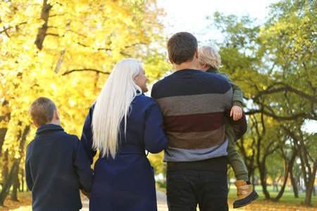 A rear view of family with two small children on a walk in autumn nature. Horizontal photo