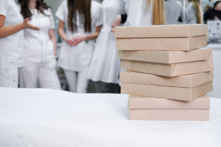 Stacked catering boxes with appetizers on a table in the foreground, with a group of medical...