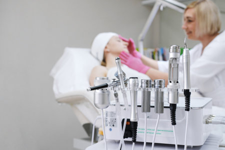 Skin rejuvenation and treatment equipment on display with a blurred background of a patient and a cosmetologist in a clinic.の写真素材