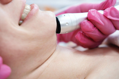 Gloved hands perform a facial rejuvenation treatment using an oxygen mesotherapy handpiece on a...