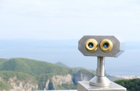 Silver and gold binoculars face the sea, providing tourists with a panoramic view of the distant...