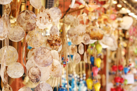 Handcrafted seashell wind chimes and colorful ornaments for sale at a sunny local Mediterranean...