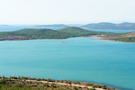 A captivating aerial view of the Aegean Sea turquoise waters with scattered islands and a coastal road in Turkeyの写真素材