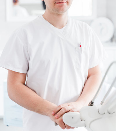 Close-up of a dentist in a modern clinic setting. The dentist is wearing a white uniform, emphasizing professionalism and cleanliness.の写真素材