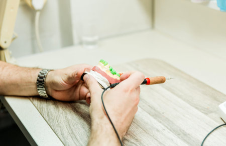 A dentist is carefully working on a dental model with a specialized tool, demonstrating precision...