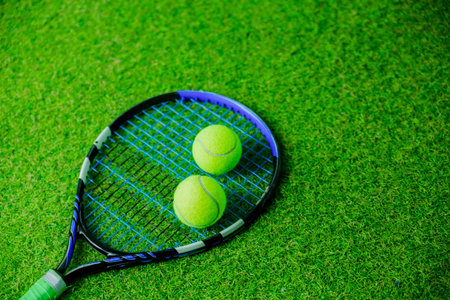 Overhead view of tennis racket and two tennis balls on a green grass court. Horizontal photo.の写真素材