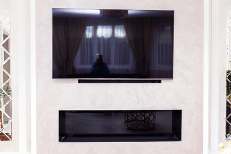 A modern living room featuring a wall-mounted television and an electric fireplace below.の写真素材