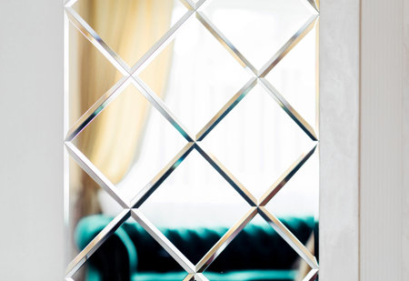 Close-up view of a geometric patterned mirror featuring diamond shapes, adding a modern touch to the interior design.の写真素材