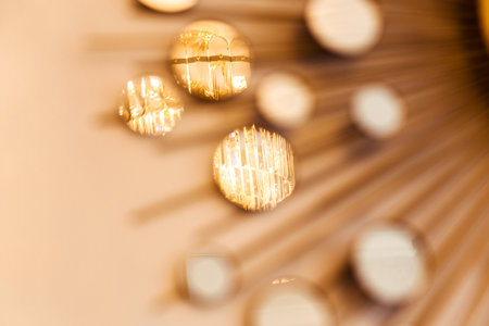 A close-up of a sun-shaped mirror wall decor piece, capturing detailed reflections. The decor is elegant, reflective, and illuminated by evening light.の写真素材