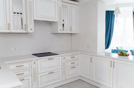 Luxurious white kitchen with intricate gold details and modern appliances. Bright and spacious interior design with a view into a stylish dining area.の写真素材