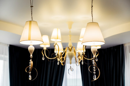 Close-up of elegant chandeliers with multiple lamps and crystal decorations in a modern home, emphasizing the luxury interior design.の写真素材