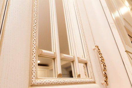 Close-up of an intricately designed kitchen cabinet door. The panel features an ornate pattern with a reflective surface.の写真素材