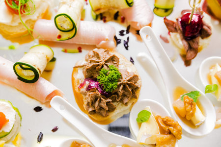 Variety of gourmet appetizers with meats, vegetables, and garnishes on white plate. Horizontal photo. Top view.の写真素材