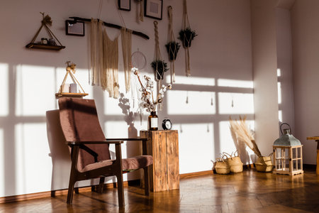 Sunlit living room corner with a cozy chair, wooden table, cotton stems, and bohemian decor. Warm, inviting ambiance.の写真素材