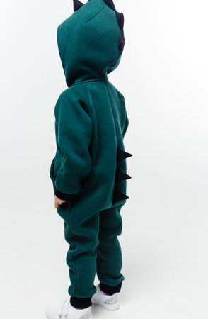 A boy in a green jumpsuit with black spikes, standing sideways. Vertical photo.の写真素材