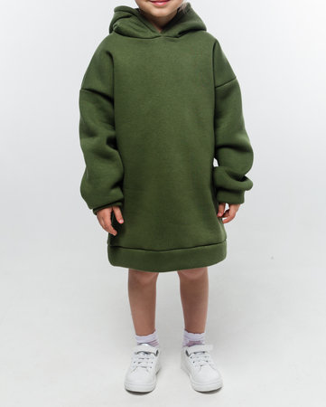 A small girl wearing a green oversized hoodie dress with long sleeves, posing confidently in a studio setting.の写真素材