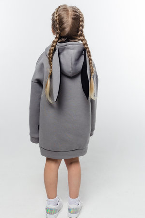 A young child wearing a gray hoodie with black bunny ears on the hood. The child is standing with their back to the camera,の写真素材