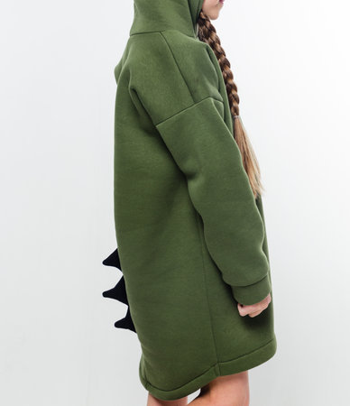 A young child wearing a green hoodie with black dinosaur spikes, standing sideways against a white background. Vertical photoの写真素材