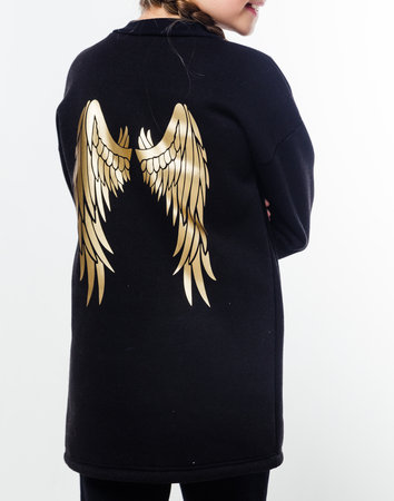 A small child wearing a black hoodie with golden wings on the back, posing sideways against a white background. Vertical photoの写真素材