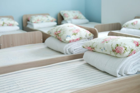 Neatly arranged sleeping areas in a kindergarten feature cozy beds with floral pillows, inviting a peaceful atmosphere for children to relax and rejuvenateの写真素材