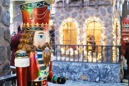 Nutcracker figure is prominently displayed near a whimsical fairytale town scene, featuring sparkling lights and festive decorations, creating a joyful holiday ambianceの写真素材