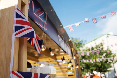 Flags decorate a lively market stall, enhancing the festive ambiance with bright lights and a clear blue skyの写真素材