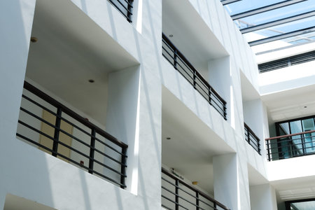 Contemporary building interior showcasing white walls and black railings on balconies, illuminated...