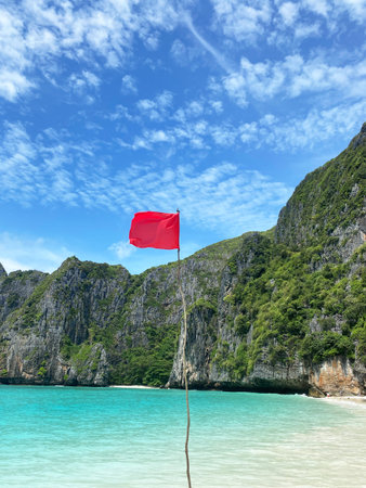 Red flag indicates no swimming at Maya Bay Island, with stunning cliffs and clear turquoise waters visible under a bright blue skyの写真素材