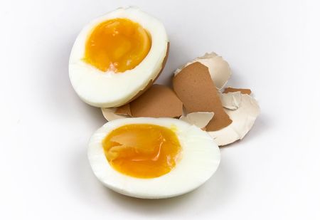 Boiled egg cut in half over egg's shellsの写真素材