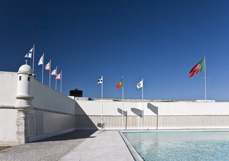 Old royal flags and actual Portuguese national flag flying over an ancient fortress in Lisbon,...