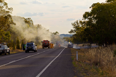 Fire fighters and police attending a car fire on the road near Parkes, NSW, Australia