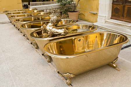Set of empty bronze bathtubs with a statue of a dressed man inside one of tubs decorating the inner patio of a building in Grasse, Riviera, Franceのeditorial素材