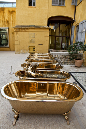 Set of empty bronze bathtubs with a statue of a dressed man inside one of tubs decorating the inner patio of a building in Grasse, Riviera, Franceのeditorial素材