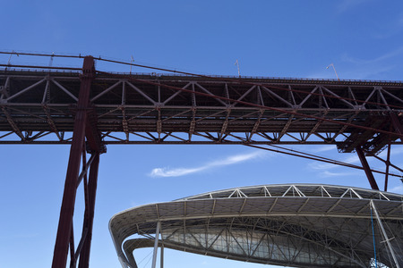 View of two iconic metallic structures, the 25th of April Bridge and the Tennis Court roof, in Lisbon, Portugalの写真素材