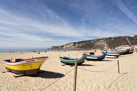 Traditional fishing boats on the magnificent beach of the village of Nazare, Portugalのeditorial素材