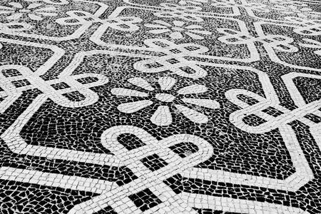Traditional style Portuguese pavement, designed with black and White stones of basalt and limestone, used in pedestrian areas of Portugalの写真素材