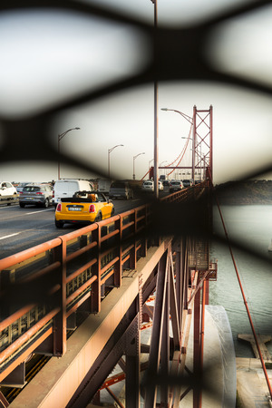 The 25th of April Bridge seen through a lateral grid on the panoramic belvedere in Lisbon, Portugalのeditorial素材