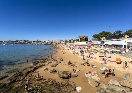 View of the crowded pretty little beach named Praia da Duquesa along the beach promenade between the towns of Estoril and Cascais, nearby Lisbon, Portugalの写真素材