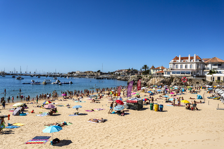 View of the crowded pretty little beach named Praia da ConceicÃ£o along the beach promenade between the towns of Estoril and Cascais, nearby Lisbon, Portugalのeditorial素材