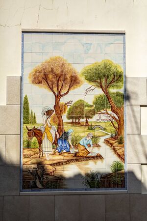 Detail of the beautiful polychromatic ceramic tiles panel depicting women washing clothes and linen on the river, on a wall in Tentugal, Coimbra, Portugalの写真素材