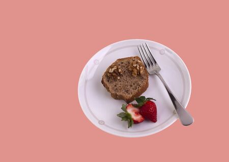 Portion of homemade walnut cake and strawberry on a pink background with writing spaceの写真素材